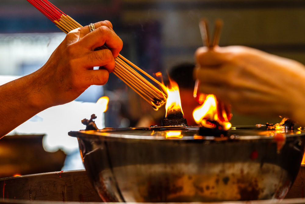 ผู้ที่เกิดปีชงกำลังจุดธูปไหว้เทพเจ้าไท่ส่วยเพื่อเสริมความสิริมงคล